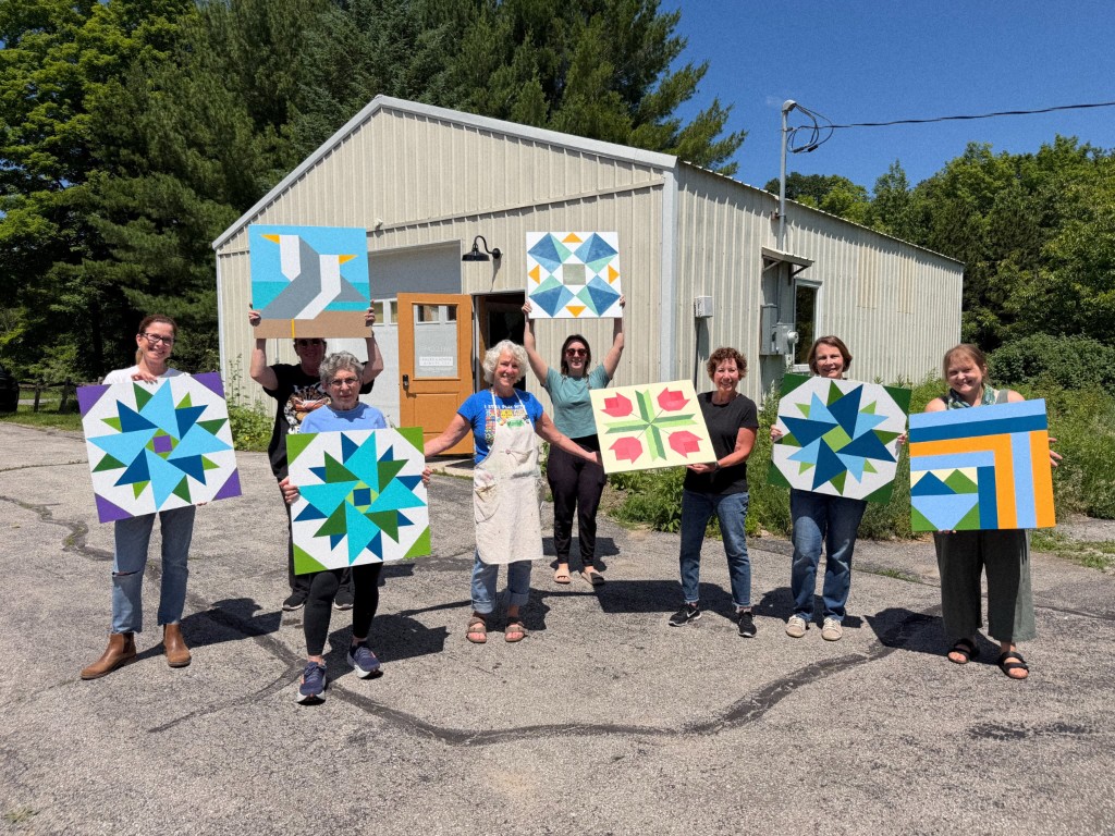 Students holding painted barn quilts after a Green Door Folk School class